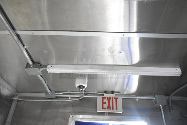 Brand new 2021 Rock Solid Cargo 24' fast food trailer interior, featuring overhead lighting, exit sign, and metal piping.