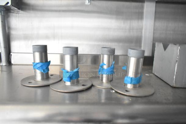 Metal fittings wrapped with blue tape on a stainless steel surface inside a new 2021 Rock Solid Cargo mobile kitchen trailer.