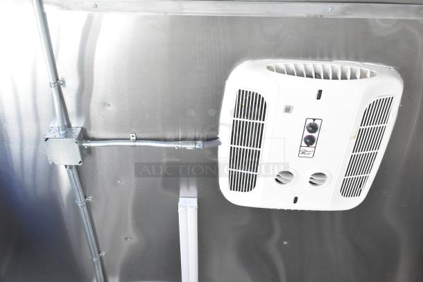 Interior of a Rock Solid Cargo mobile kitchen trailer showing a white wall-mounted vent system, metallic surfaces, and wiring.