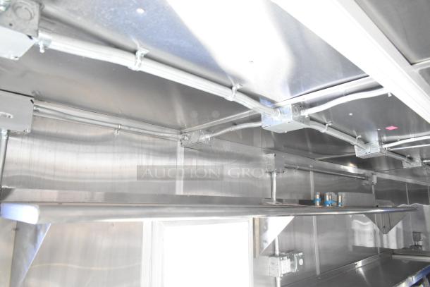 Interior view of a brand new 2021 Rock Solid Cargo 24' fast food trailer with stainless steel shelving and electrical fittings.