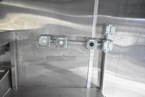 Interior of a brand new Rock Solid Cargo 24' mobile kitchen trailer showing electrical outlets and stainless steel walls.