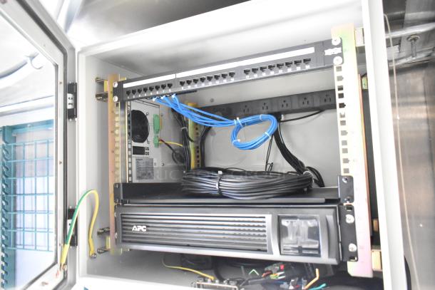 Interior view of Rock Solid Cargo fast food trailer, showing network equipment with cables and APC unit.