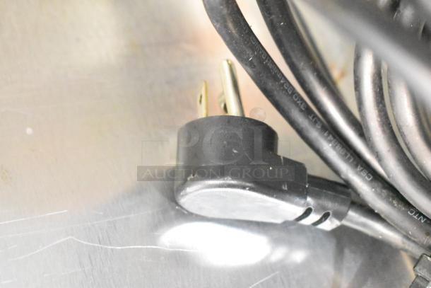 2019 Delfield 406P-STAR2 undercounter cooler plug. 115 Volts, 1 Phase. Coiled black cord on metallic surface.