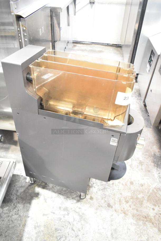 Commercial countertop coffee tower machine, gray metal, acrylic containers, on wheels. Tag marked "23" visible.