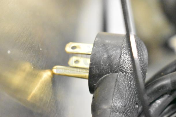 Close-up of a power plug for a Delfield 406P-STAR2 Undercounter Cooler, showing prongs and textured grip.