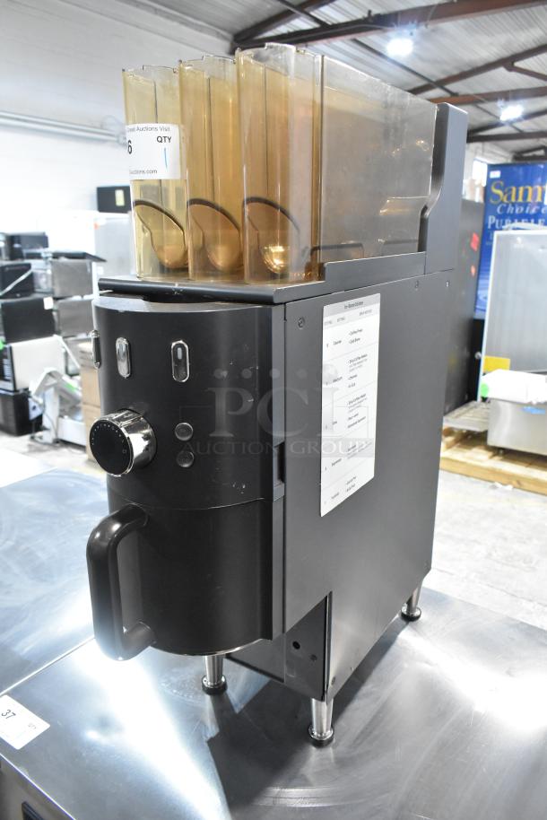 Commercial countertop coffee tower machine, black with multiple compartments, chrome knobs, and visible settings chart.