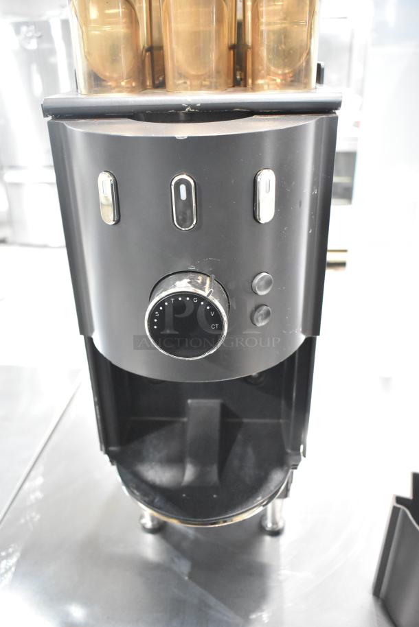 Commercial countertop coffee tower machine, black finish, with three transparent hoppers and control dials, in good condition.