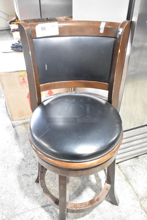 Bar height chair with wood pattern frame and black cushioned seat. Minor scratches on wood, tag indicating quantity of 55.