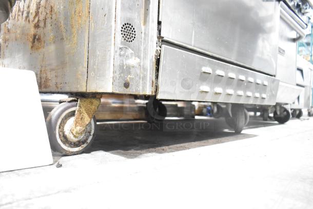 Jade Range commercial gas 6-burner 2-tier range with oven, backsplash, and commercial casters, showing signs of wear.