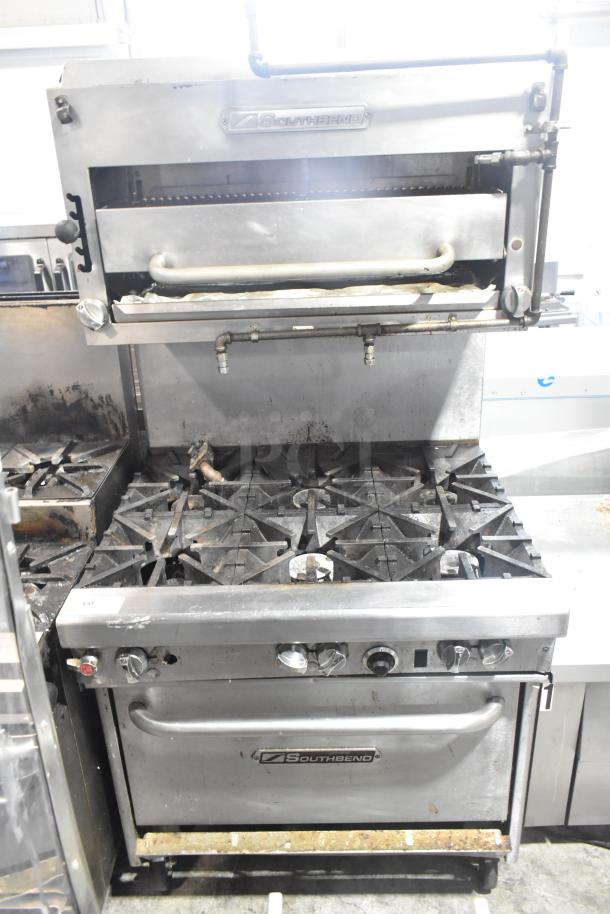 Southbend commercial gas range, six burners, oven, salamander cheese melter, backsplash, on casters, visible wear.