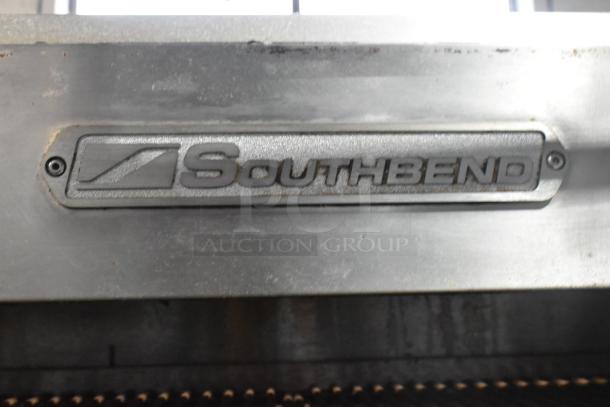 Southbend logo on commercial gas-powered 6 burner range with oven, salamander cheese melter, and backsplash on casters.