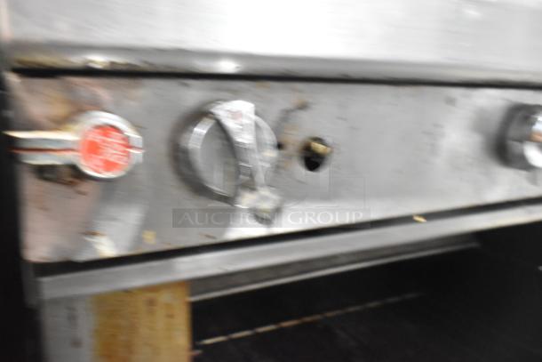 Southbend commercial 6 burner gas range with oven and salamander, featuring knobs and visible wear, mounted on casters.