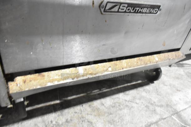 Southbend commercial gas range with 6 burners, oven, salamander cheese melter, and back splash. Visible wear on surface.