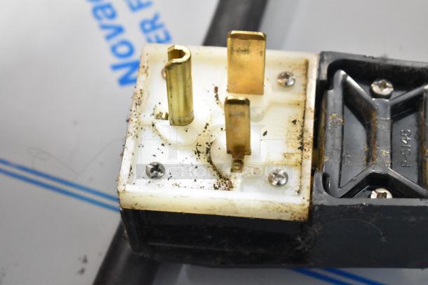 Close-up of a commercial power plug from a Thermoplan Mastrena espresso machine, showing three prongs and minor dirt.