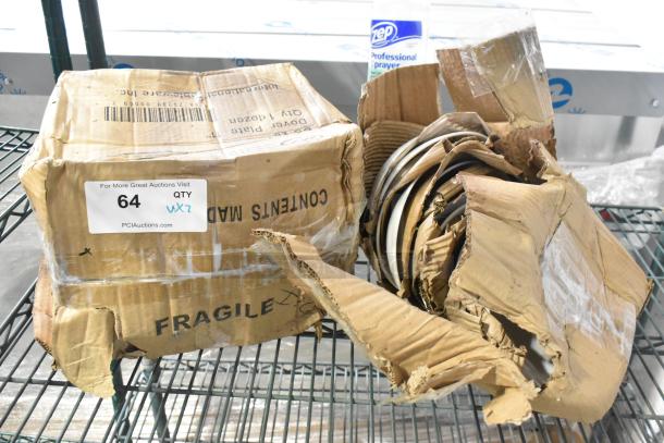 Opened cardboard box containing International Tableware Dover 11" round porcelain plates and Acope bowls with visible damage.