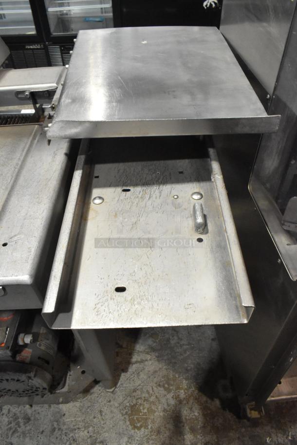 Commercial floor-style meat saw, metal construction with wear marks. Operates on 208-220/440 volts. Durable for heavy use.