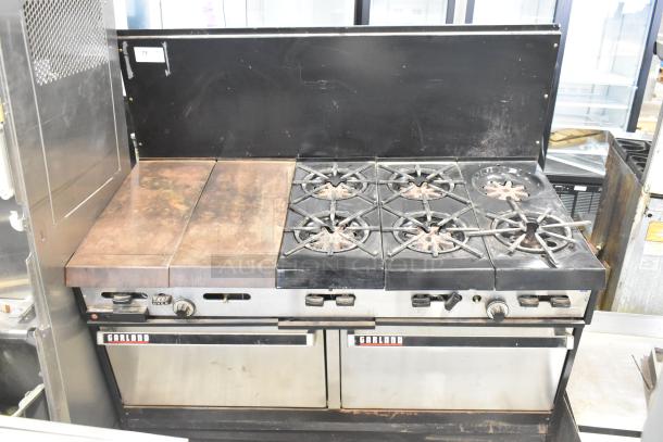 Garland commercial gas-powered griddle with 6-burner range, 2 ovens, and backsplash. Signs of use, model plate visible.