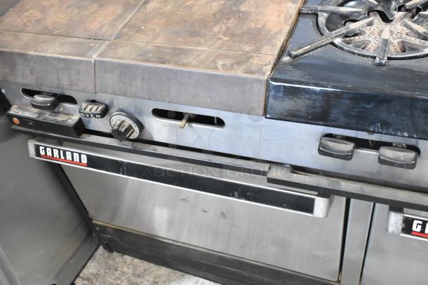 Garland commercial gas-powered flat top griddle with 6-burner range, 2 ovens, and back splash. Garland branding visible.
