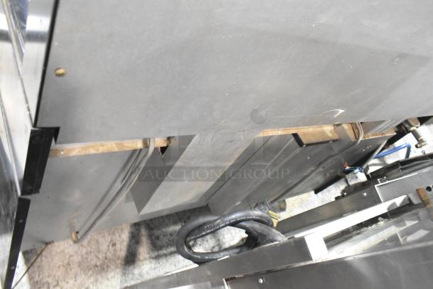 Garland commercial gas griddle with six-burner range, dual ovens, and backsplash. Good condition, rear view showing utility connections.