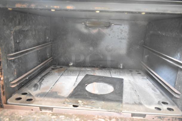 Interior view of Garland commercial oven, showing worn metal surfaces and baking racks.
