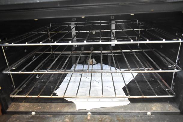 Garland commercial oven interior with wire racks and paper documents inside. Suitable for a professional kitchen setup.