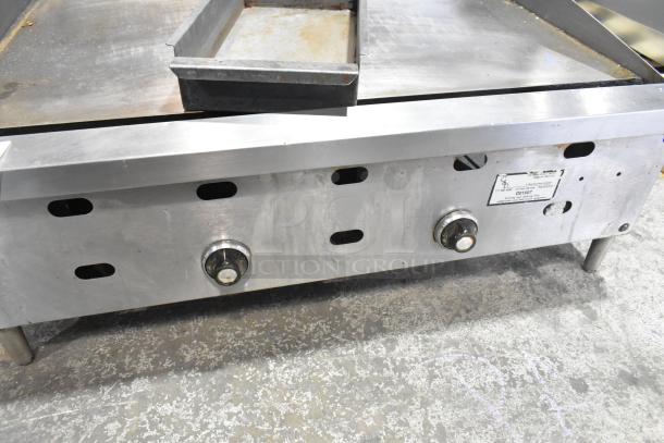 Commercial countertop gas-powered flat top griddle with dual control knobs and a stainless steel surface, showing light wear.