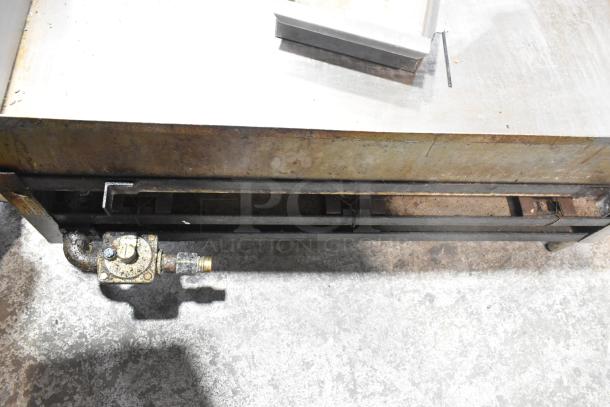 Commercial countertop gas-powered flat top griddle, showing heavy-duty metal construction, in used condition with visible staining and wear.