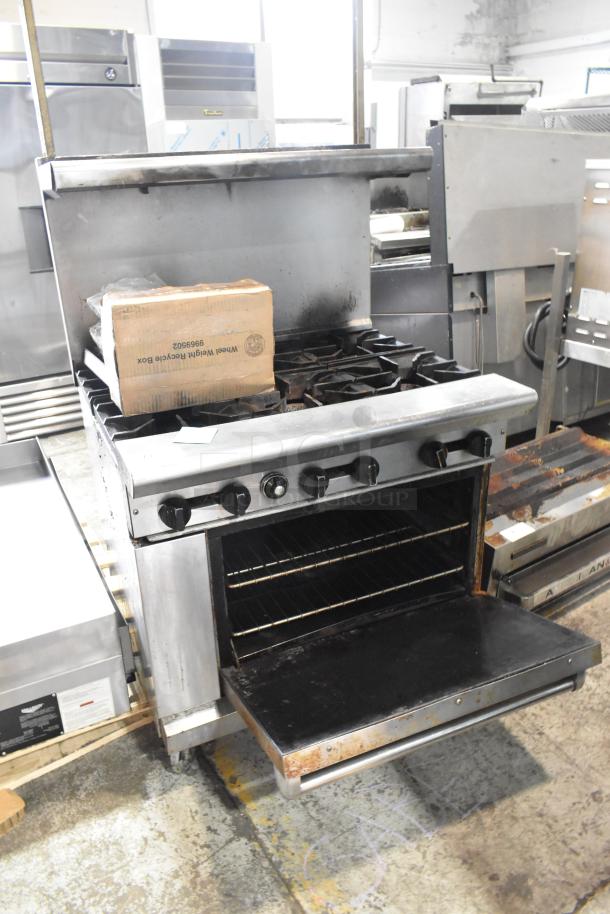 American Range commercial 6-burner gas range with oven, over-shelf, backsplash, on casters, showing signs of use.