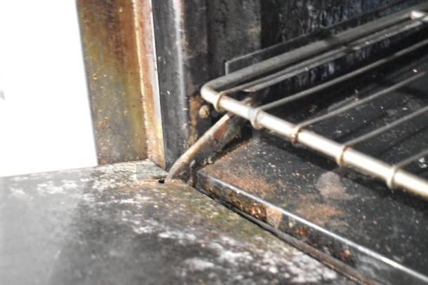 American Range 6 burner commercial gas range interior detail showing wear and rust. Features include oven, overshelf, backsplash.