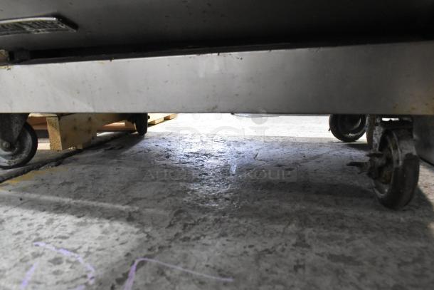 American Range commercial gas-powered 6-burner range on commercial casters. Features oven, overshelf, and backsplash.