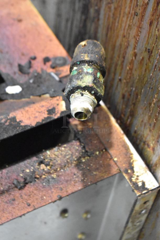 American Range commercial gas cheese melter, visible wear and grease, showing connection fitting and metal surfaces.