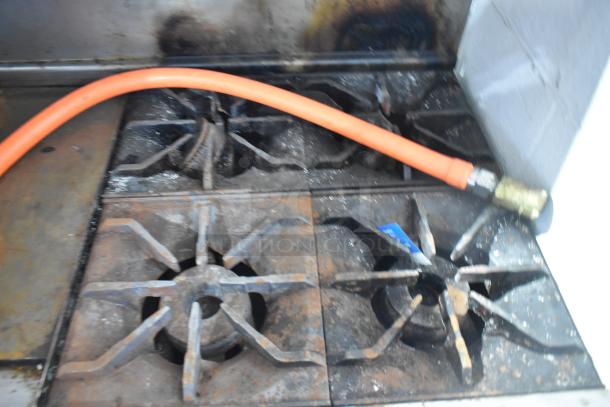 Imperial IR4-G12 commercial gas range with flat top griddle, four burners, and visible wear. Includes overshelf and back splash.