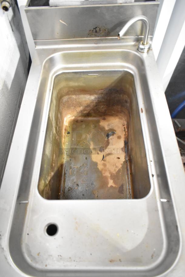 Commercial floor-style pasta cooker with stainless steel basin, faucet, and drainage hole. Visible wear and stains inside.