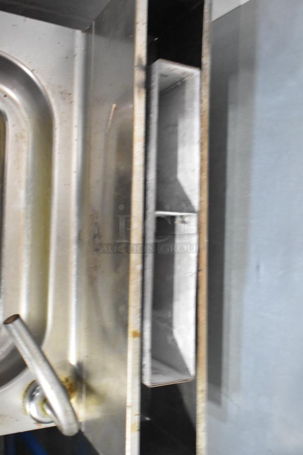 Commercial floor-style pasta cooker, stainless steel, visible wear and discoloration, large volume capacity.