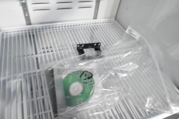 2019 Habco SE18HC commercial reach-in cooler interior, showing shelving and a packaged accessory on a white grid shelf.