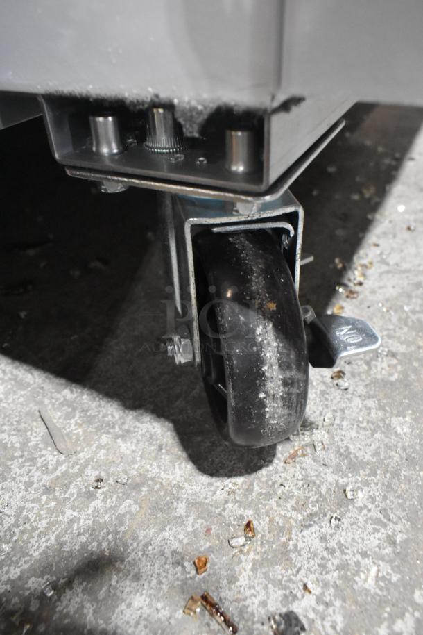 Broken wheel caster detail of Avantco 178GDC40HCW merchandiser refrigerator. Visible glass pieces around it.
