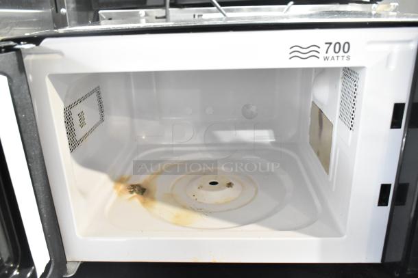 2020 Mainstays EM720CGA-B microwave oven. Interior shows signs of use with stains. 700 watts, 120 volts, 1 phase.