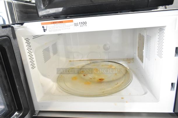 Hamilton Beach HB8436127995-03 countertop microwave with glass plate. Shows some food residue inside. 1100 watts, 120V, 1 phase.