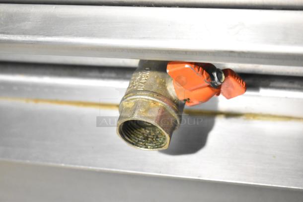 Close-up of a metal pipe fitting with a red valve handle on a Fri-jado TDR7-P rotisserie oven.