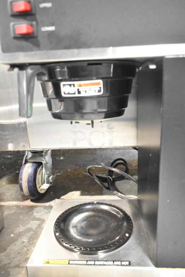 Bunn VPR 12-cup pourover coffee brewer, black, with two warmers. Visible labels indicate caution for hot surfaces.