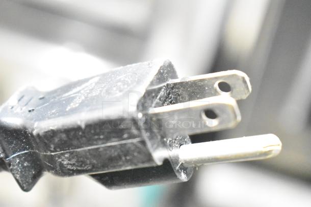 Close-up of a power plug for the 2023 Sharp R-21LVF Commercial Countertop Microwave Oven, showing a two-pronged design.