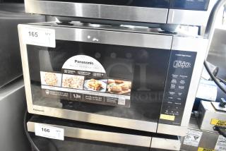 Panasonic countertop microwave oven, 1100W, used as display, missing power cord, 120V, 1 phase. Features auto defrost and reheat.