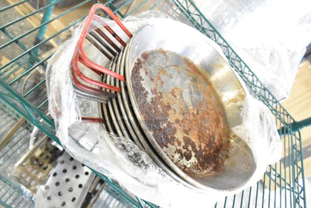 Collection of various cookware including skillets, bowls, coffee pot, and metal pot. Visible rust and wear on items.