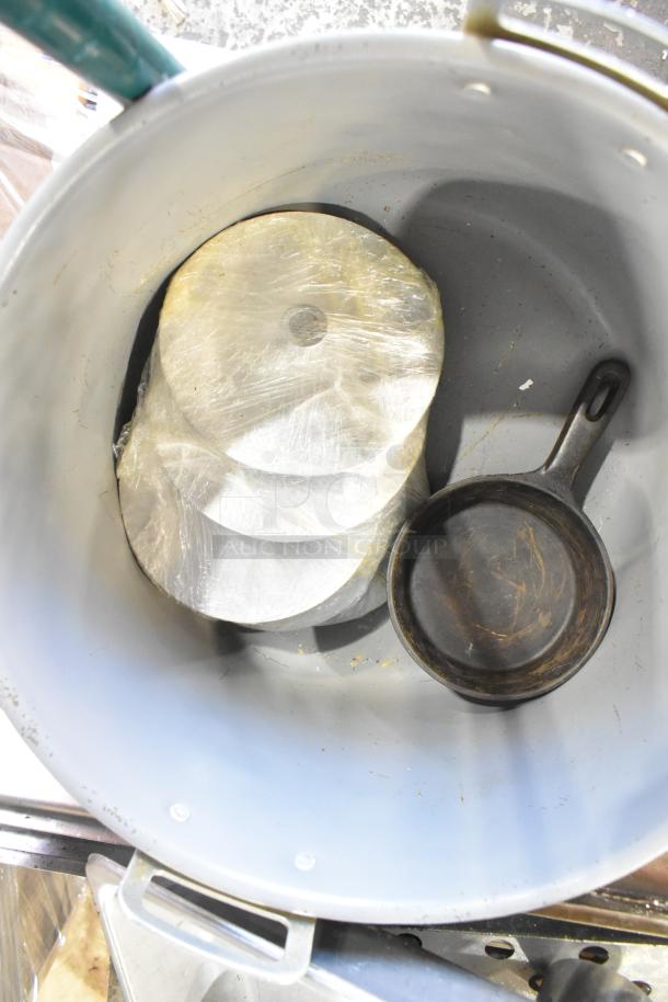 Metal pot containing a cast iron skillet and wrapped bowls; vintage kitchenware in used condition.