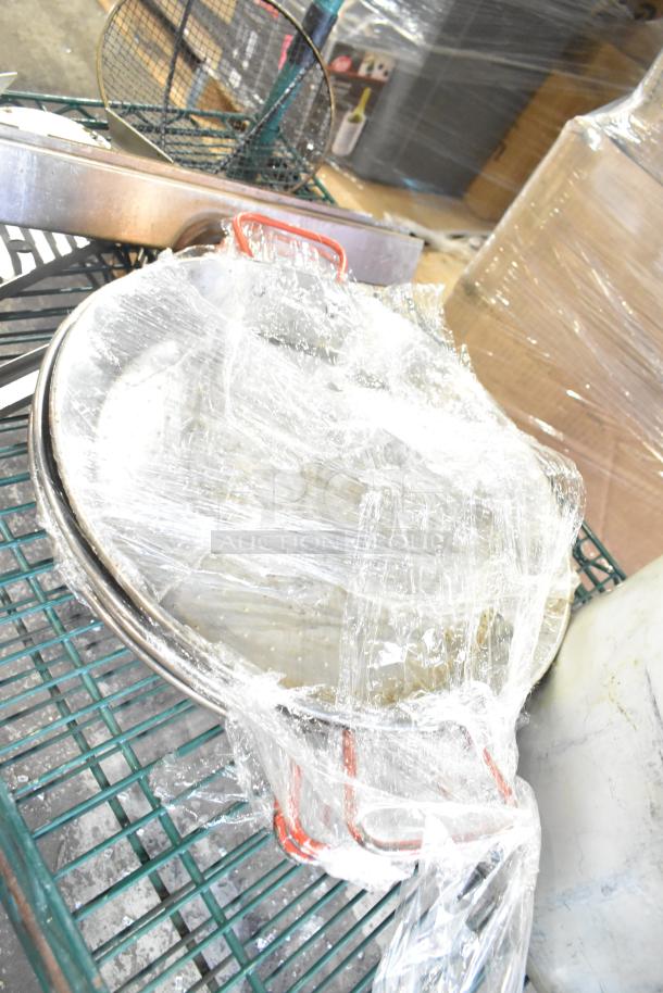 Various kitchen items wrapped in plastic, including skillets, bowls, a coffee pot, and a metal pot, on a cart.
