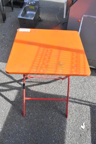Orange folding table with red metal legs, in used condition. Price tag reads "6 times your bid."