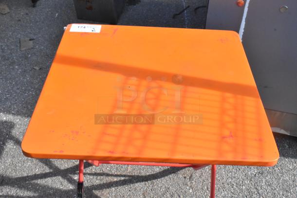 Orange folding table, square shape, slight wear visible. Auction lot includes 6 tables. Small label with number "174".