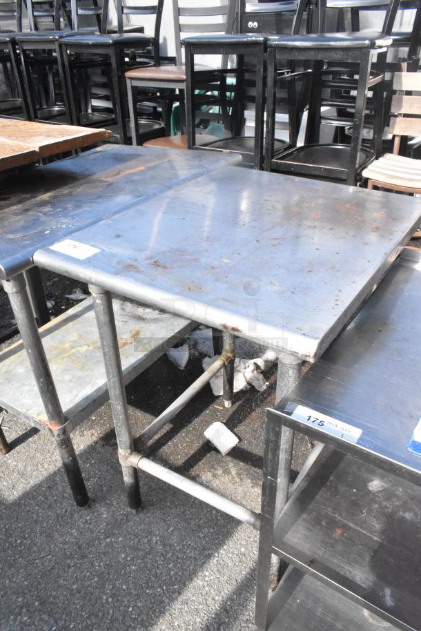 Stainless steel commercial table with a sturdy metal frame, showing signs of rust and wear. Ideal for industrial use.