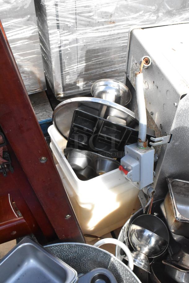 Pallet of mixed items including metal bowls, trays, and cooking equipment in varying condition.