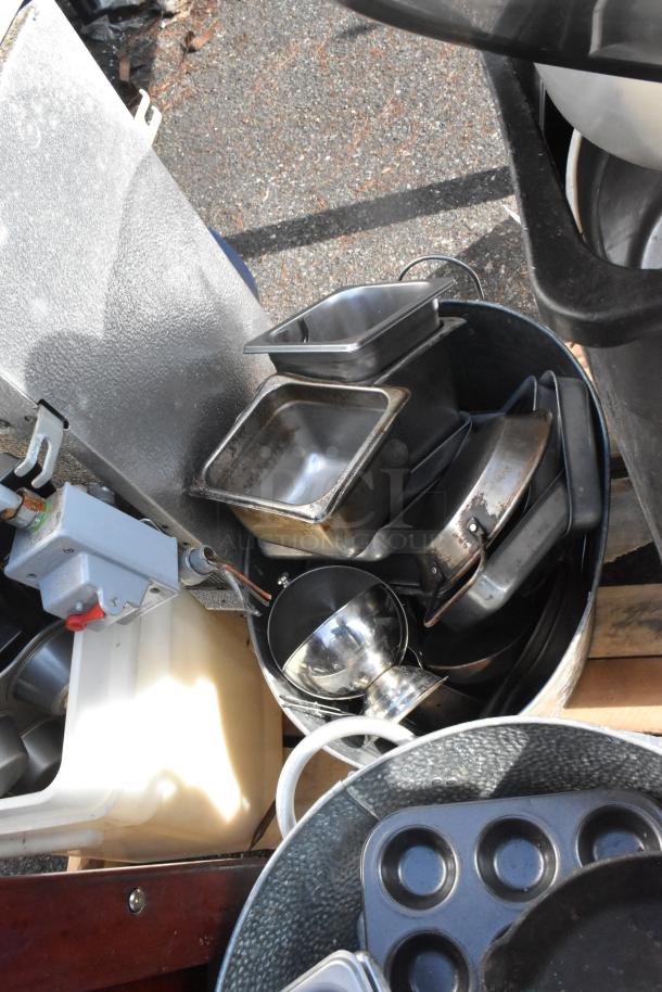 Pallet lot with various items including stainless steel pans, skillets, evaporator, and a trash can; mixed condition.